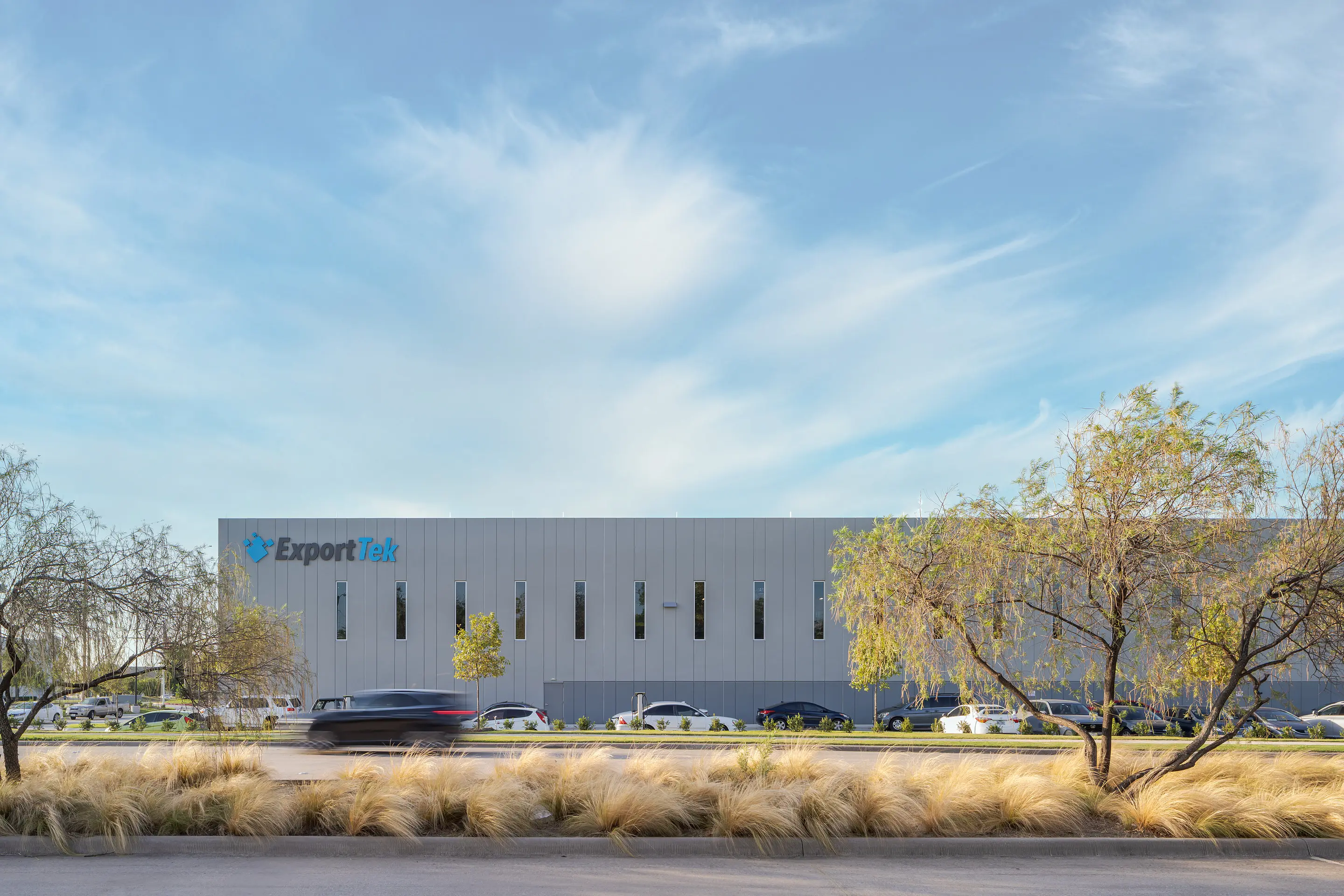 The WesternTechSystems facility facade behind ornamental grasses at dusk
