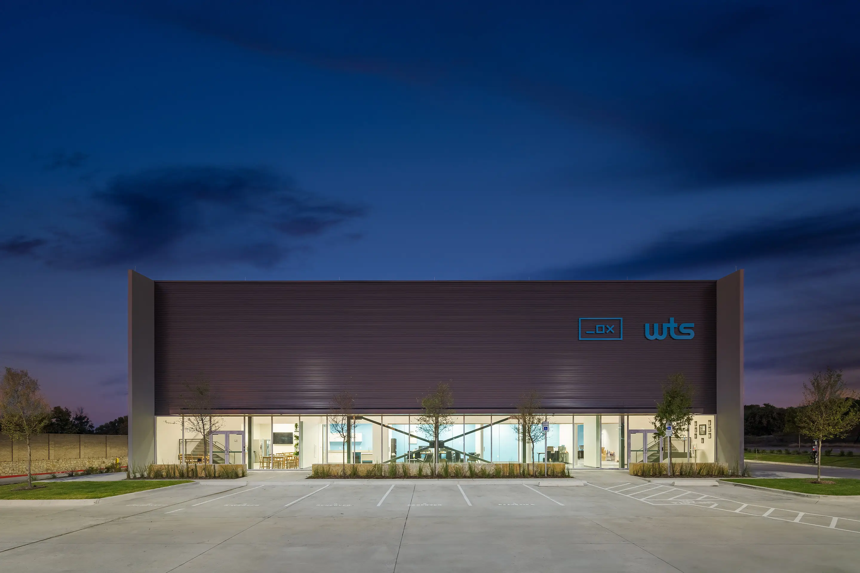The lit glass frontage of the WesternTechSystems facility at night
