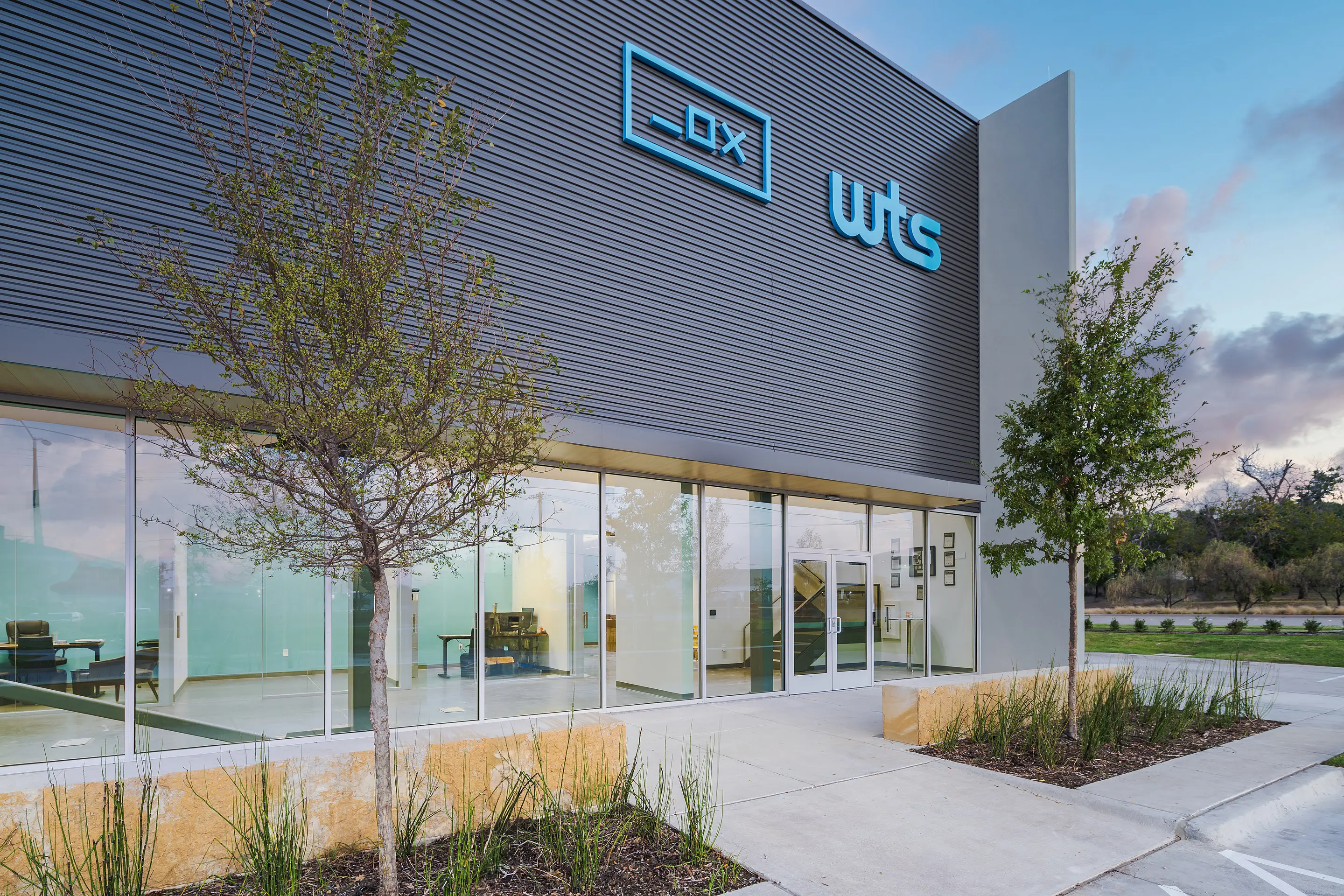 The main entrance of the WesternTechSystems facility in Lewisville, Texas at dusk, with the illuminated company signage
