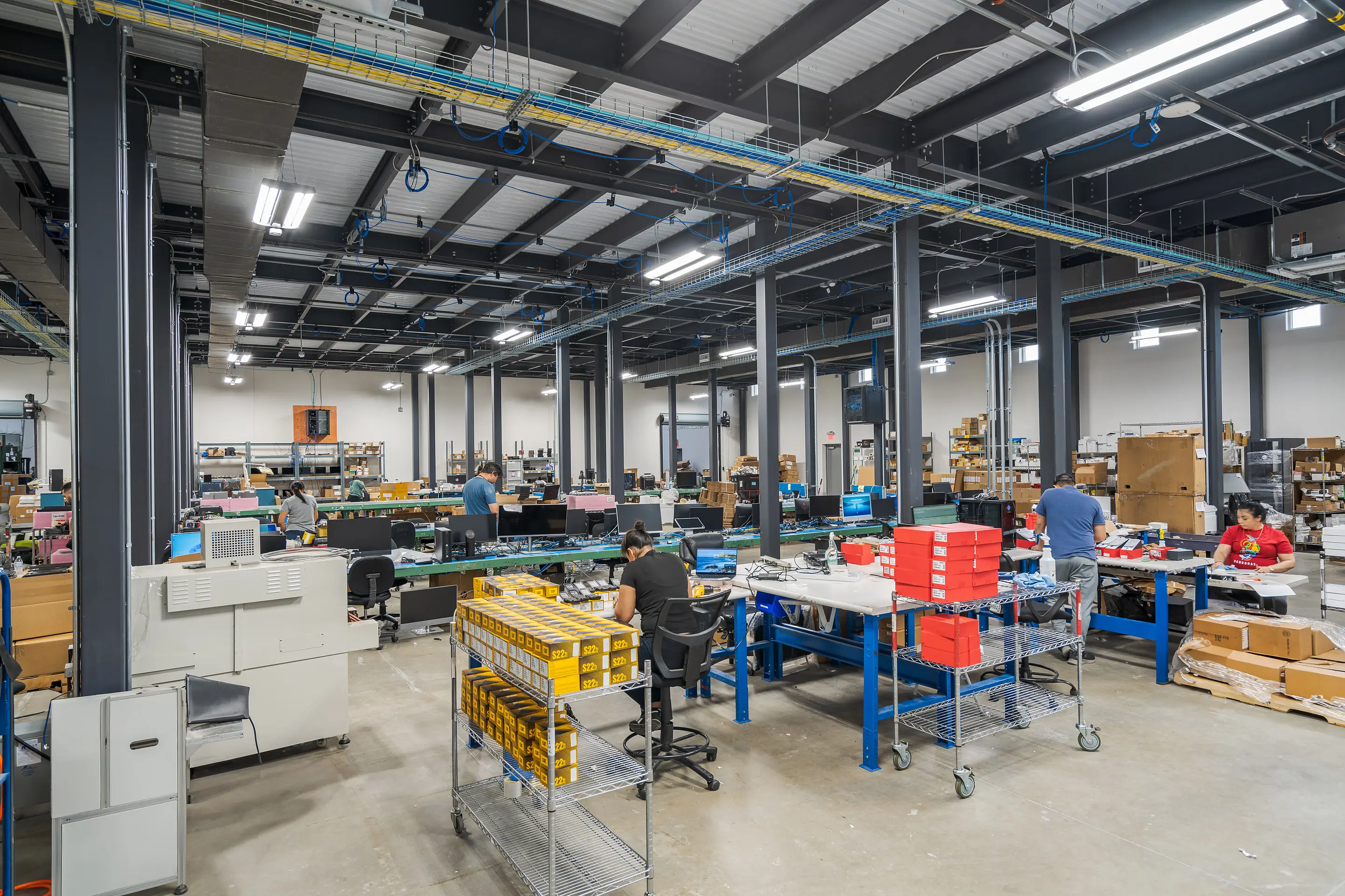 Technicians working at blue workbenches on the WesternTechSystems processing floor